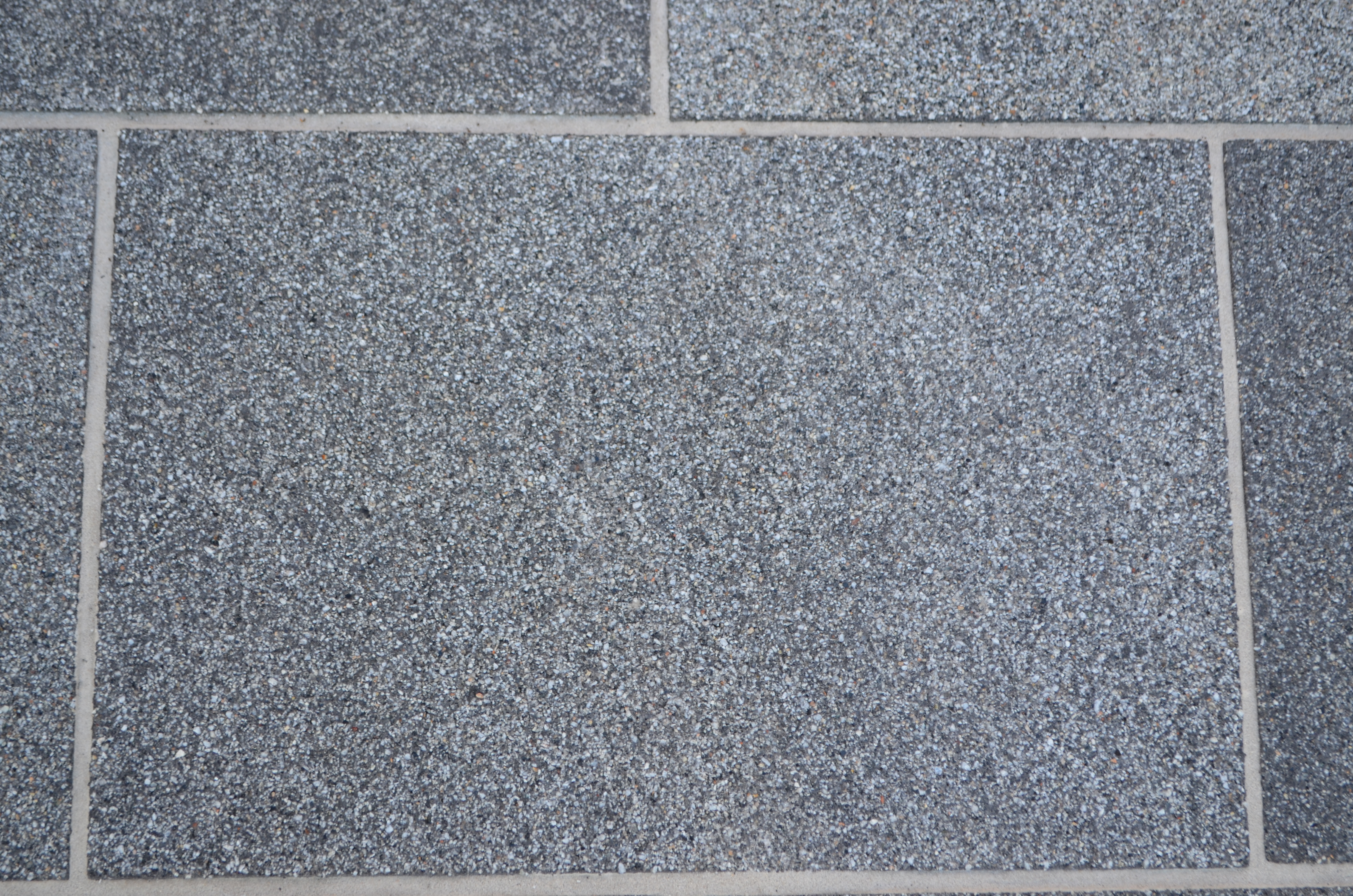 Detalle cenital de baldosas grises Zoruflex Preformado con textura de árido y juntas claras Detalle cenital de baldosas grises Zoruflex Preformado con textura de árido y juntas claras