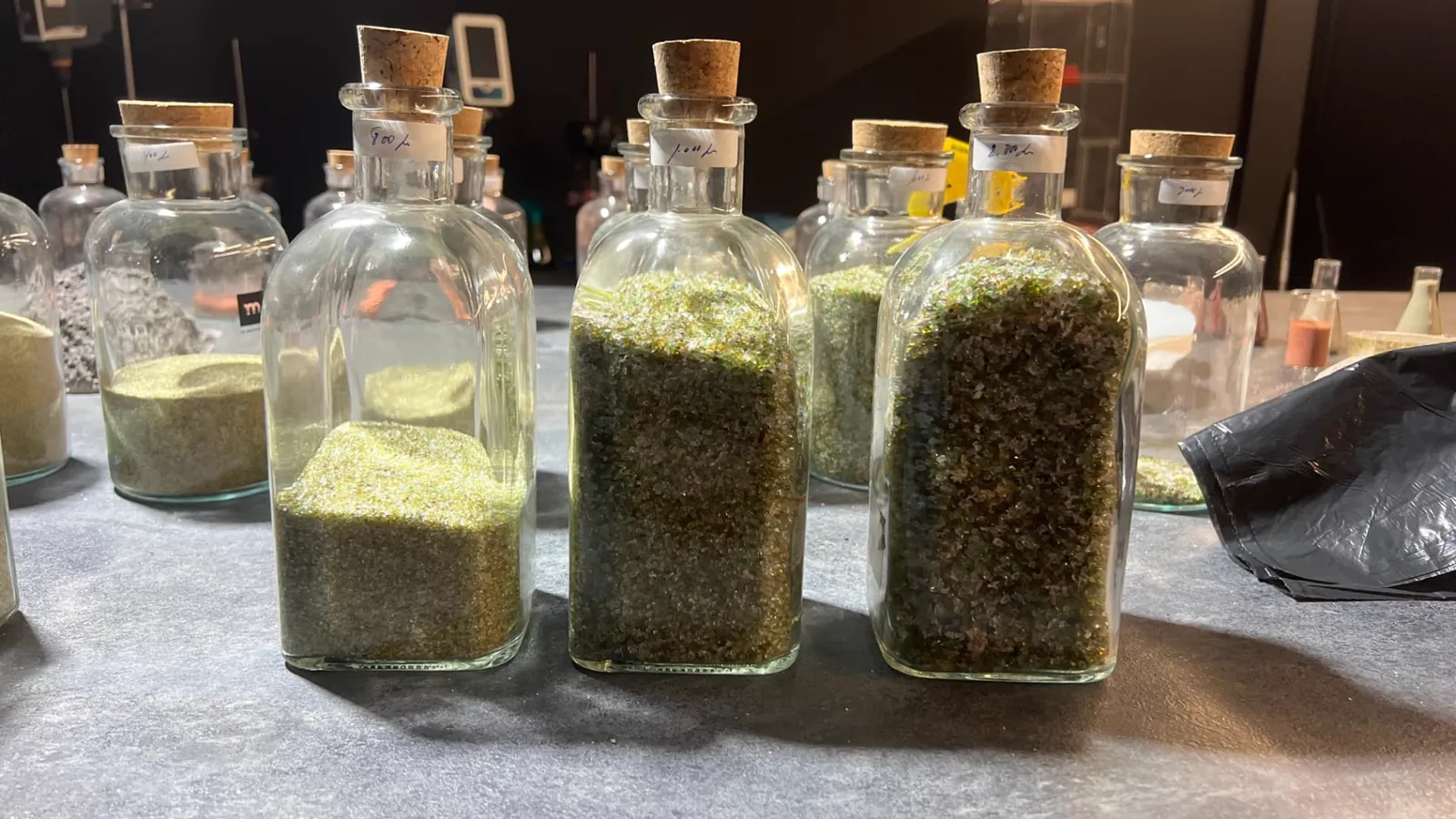 Botellas de muestra con fracciones gruesas de vidrio reciclado clasificadas por micras