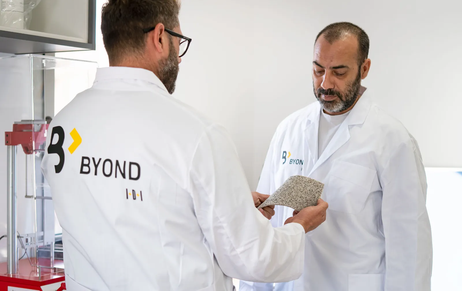 Dos técnicos examinando la flexibilidad de una muestra de pavimento Zoruflex