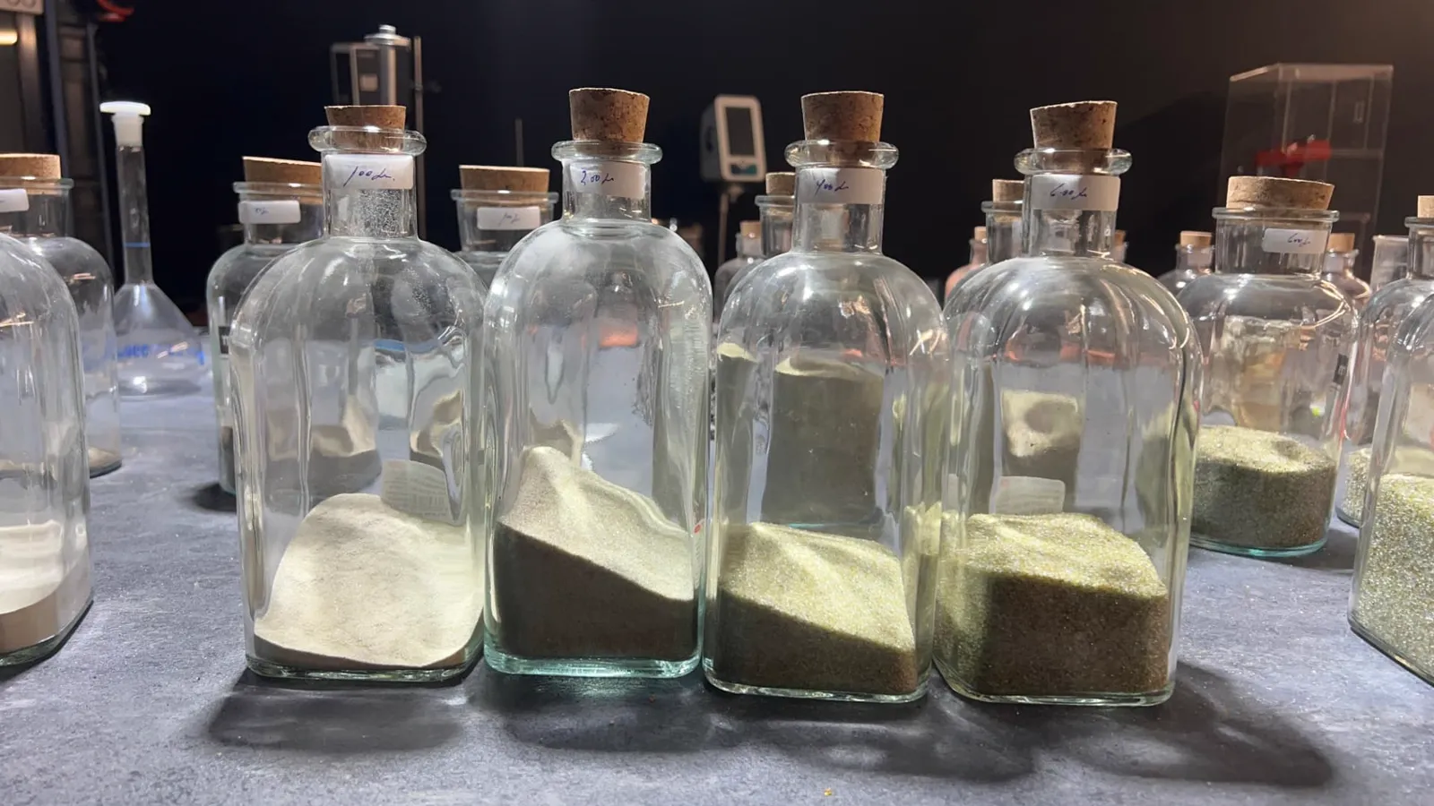 Muestras de fracciones finas de vidrio reciclado en botellas de laboratorio etiquetadas