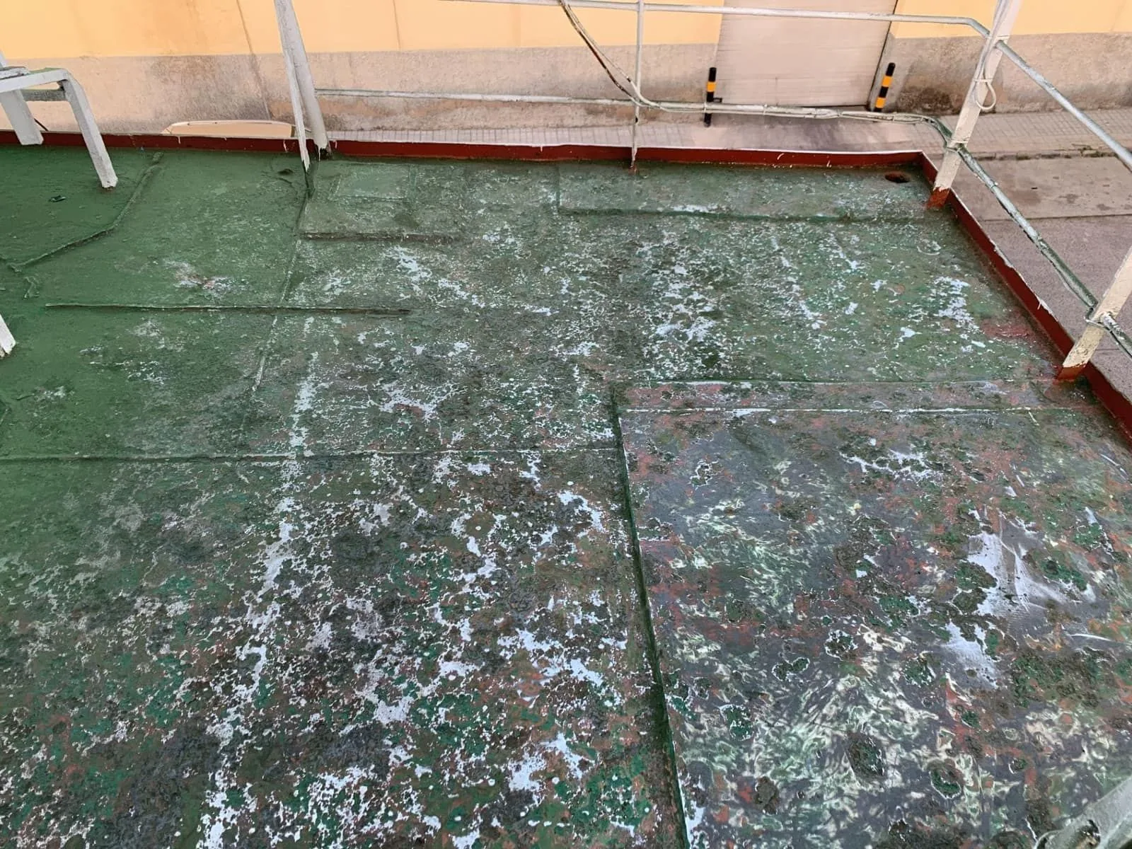 Cubierta de buque deteriorada con pintura verde levantada y restos de óxido