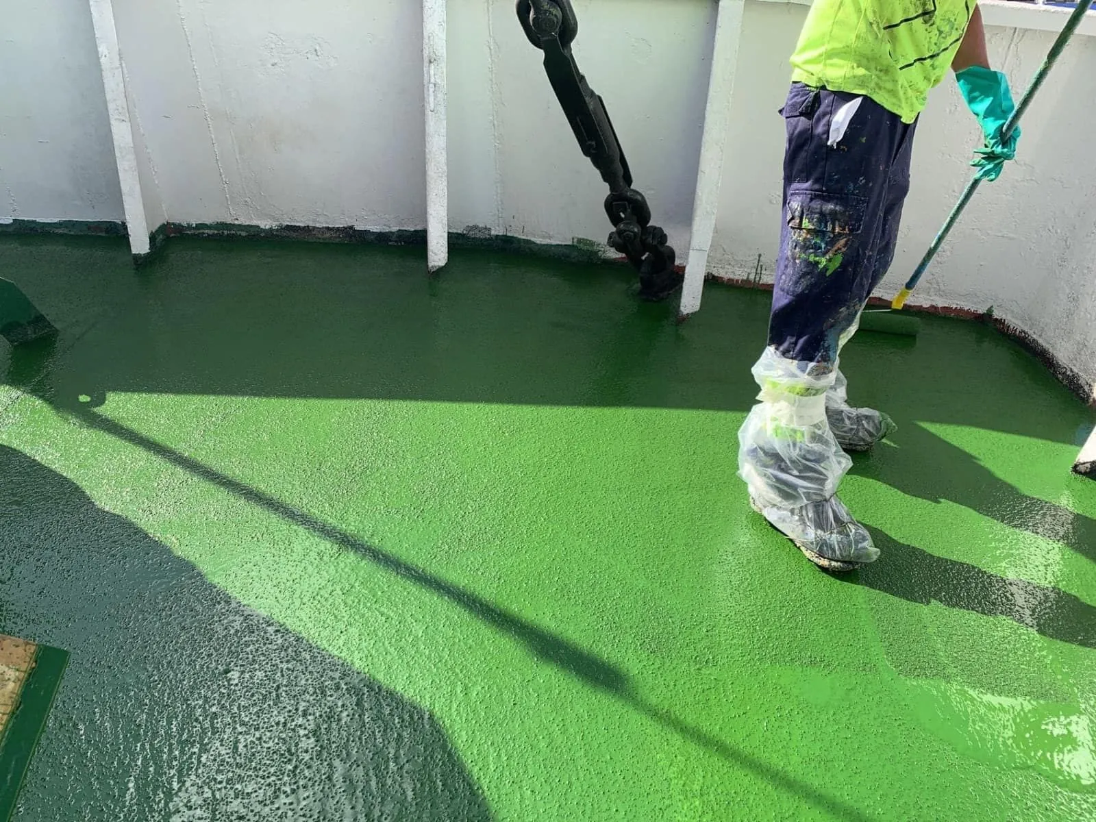 Operario aplicando con rodillo el pavimento Zoruflex Naval verde sobre cubierta