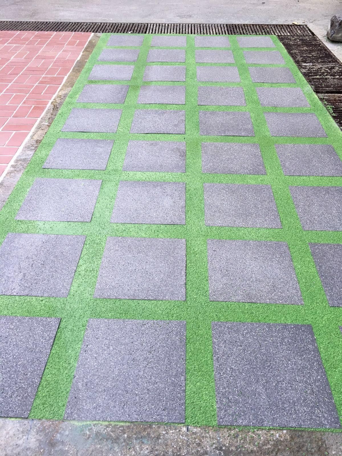 Pavimento Zoruflex en cuadrícula gris con juntas de césped artificial verde